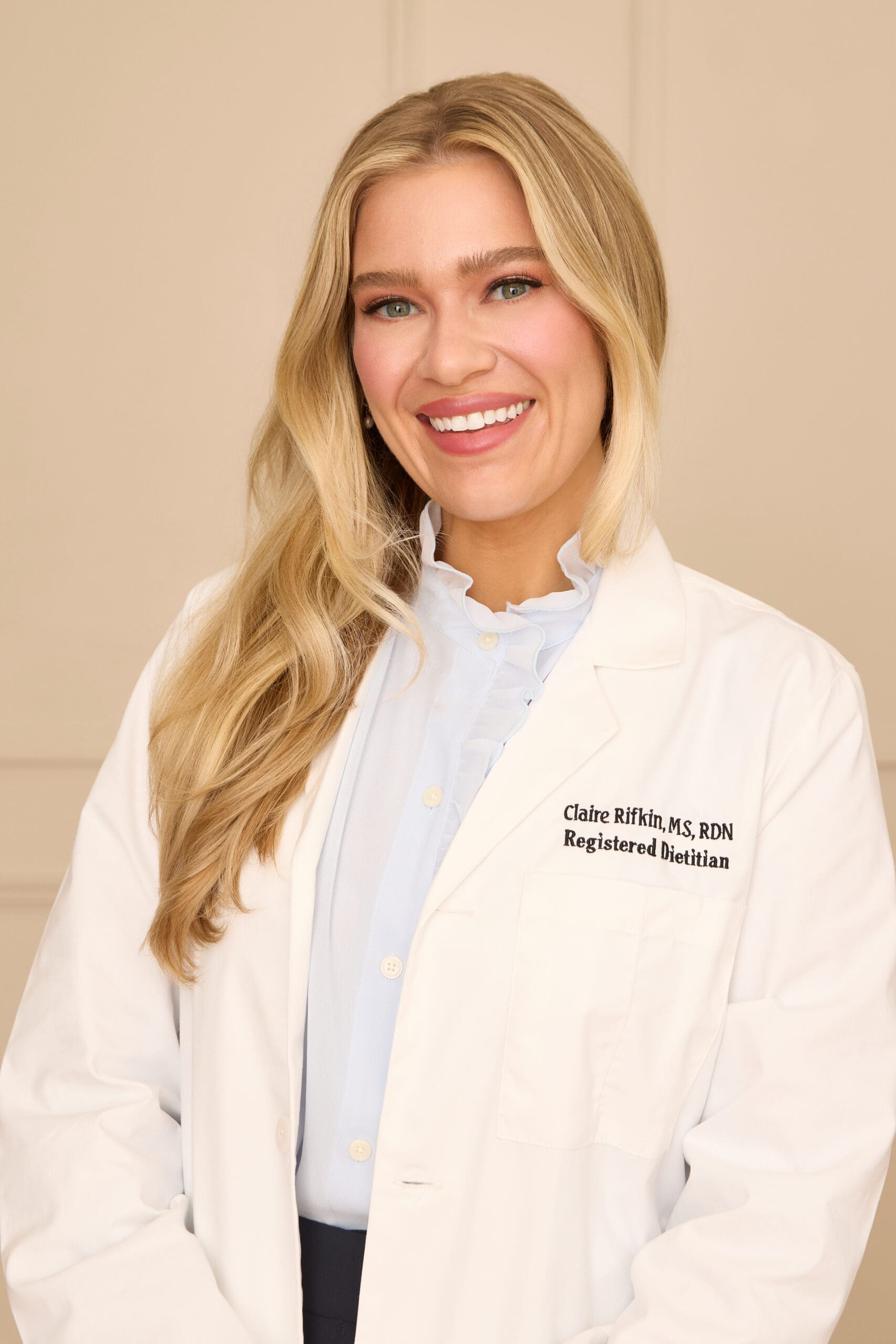 Claire Rifkin, MS, RDN, women’s health registered dietitian, smiling in a white lab coat.