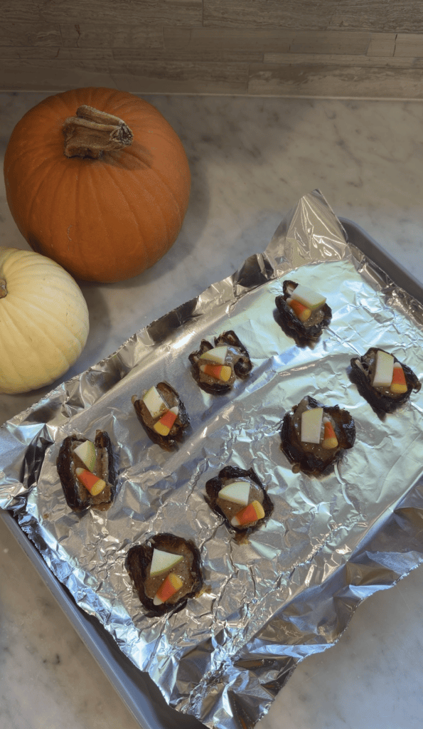 Dates topped with peanut butter, dark chocolate, caramel, small apple pieces and candy corn.