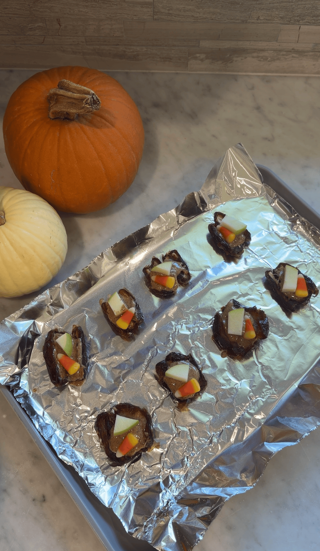 Dates topped with peanut butter, dark chocolate, caramel, small apple pieces and candy corn.